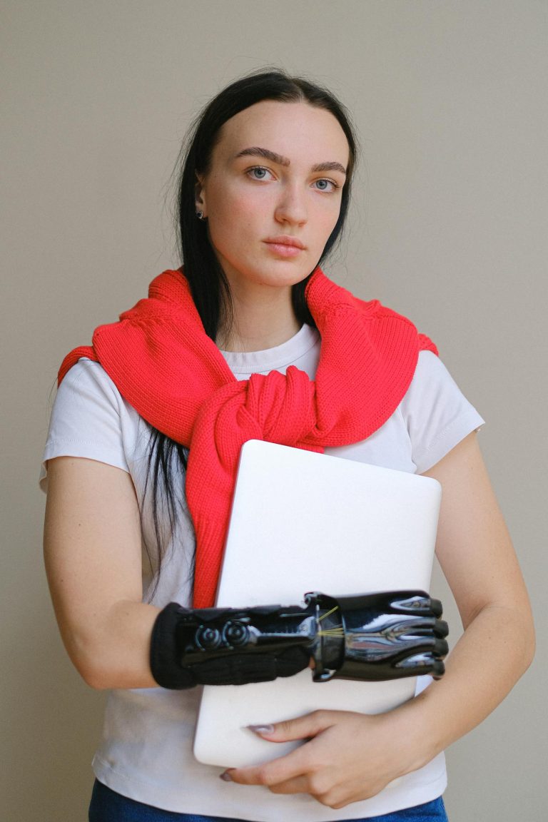 Portrait of a woman with a prosthetic arm holding a laptop, symbolizing empowerment and technology.